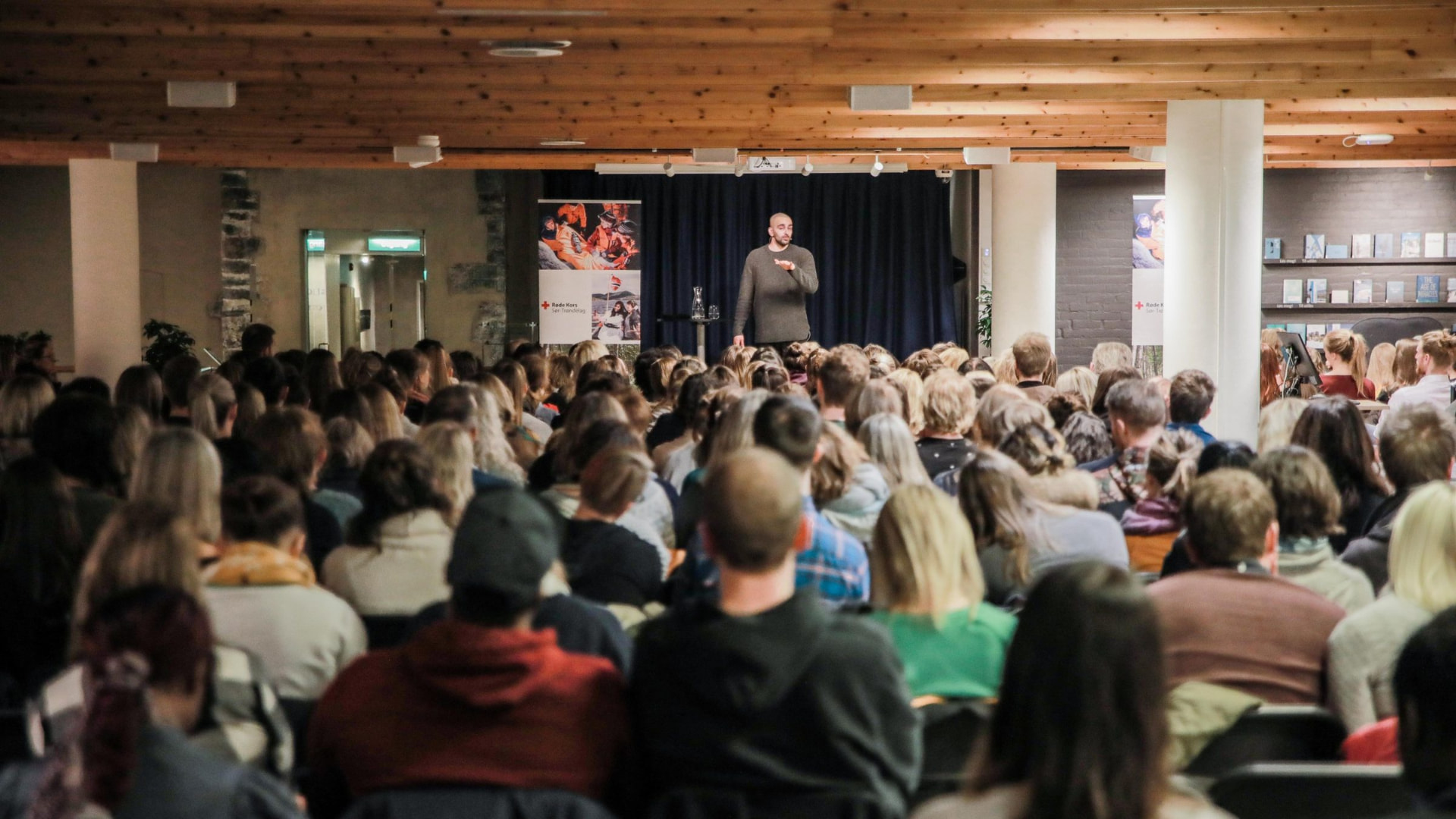 Foredragsholder på scenen foran fullsatt sal
